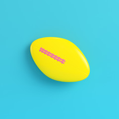 Yellow american football ball on bright blue background in pastel colors