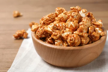 Poster Wooden bowl with tasty caramel popcorn on table © New Africa