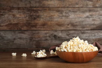 Poster Wooden bowl with tasty popcorn on table. Space for text © New Africa