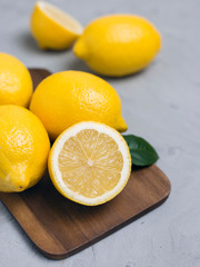 Whole and sliced lemons on wooden cutting board. Organic fresh citrus fruits