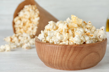 Wooden bowl with tasty popcorn on table