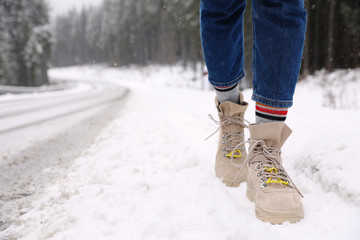 Woman walking outdoors on snowy winter day. Space for text