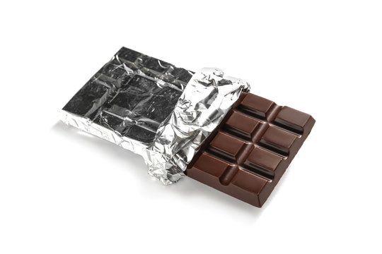 Tasty dark chocolate bar with foil on white background