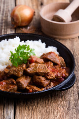 Beef stew served with white rice in cast iron skillet