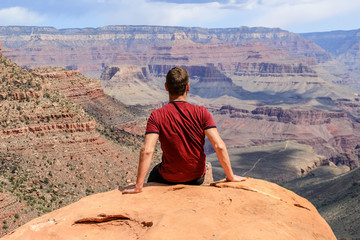 Hiker sitting at Grand Canyon looking at the view
