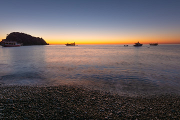 Sunrise on the Mediterranean coast, against the background of fishing boats.