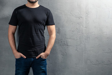 Young healthy man with black T-shirt on concrete background with copyspace for your text. Picture...
