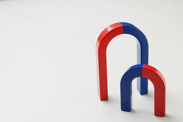 Red and blue horseshoe magnets on white background. Space for text