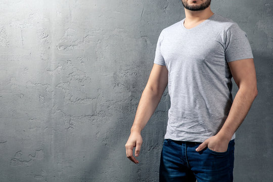 Young healthy man with grey T-shirt on concrete background with copyspace for your text. Picture without model face.