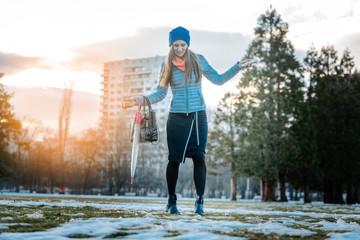 Woman having a city walk in thawing snow avoiding the puddles
