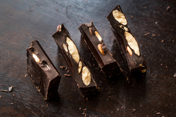 Bitter Almond Chocolate Pieces on Dark Wooden Surface.