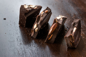 Bitter Almond Chocolate Pieces on Dark Wooden Surface.