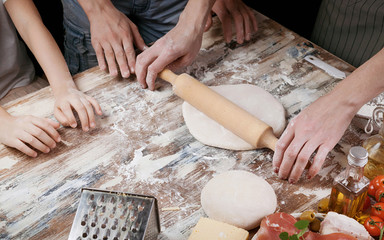 Woman with child preparing dough for homemade pizza. Light toning