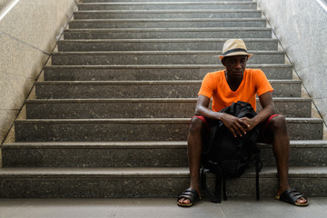 Young black African tourist man sitting on stairs