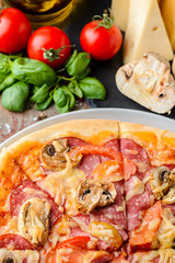Italian pizza and ingredients on a wooden background, top view