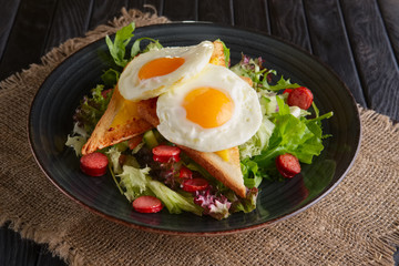 Fried eggs with toast, melted cheese and salad leaves