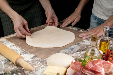 Women's hands rolling out the dough for homemade pizza