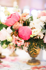 Bouquet with peach roses, pink peonies and fern in a gold vase