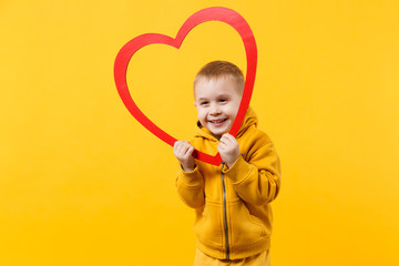 Little kid boy 3-4 years old wearing yellow clothes hold red heart isolated on orange wall background, children studio portrait. People sincere emotions childhood lifestyle concept. Mock up copy space