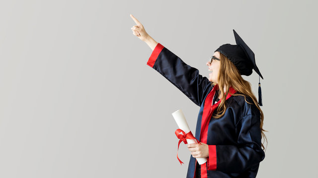 Young graduated student showing away on gray background