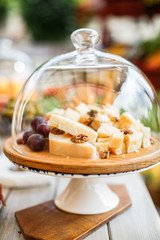 Parmesan cheese with walnuts and grapes under a glass bell jar