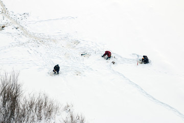 Winter fishing. Fishermen with drills catch fish from holes on a frozen river covered with snow