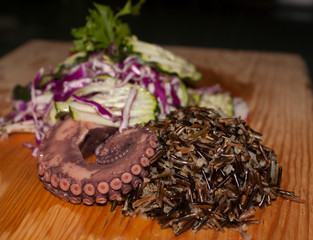 Wild rice accompanied by tentacle of octopus and salad of cucumber and purple cabbage.