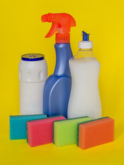 Three types of detergents for the kitchen: liquid, spray and powder and colorful foam sponge for washing dishes on a yellow background. Kitchen detergent. Household chemicals. Household chores.