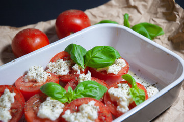 Closeup detail look on fresh vegetarian sliced and salted tomatoes ready to bake covered with...