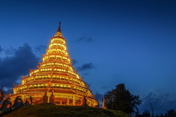 Fototapeta premium Wat Huay Pla Kang, beautiful golden pagoda chinest style decorate with lighting at night with cloudy sky background, chinese temple in Chiang Rai, Thailand.
