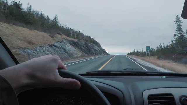 Driving POV on top of a mountains peak. The window view is larger mountains in the distance.