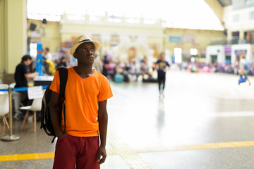 African tourist man smiling while thinking at train station