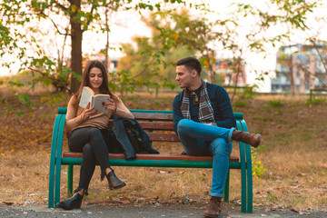 A beautiful girl is reading a book while handsome man is trying to get her attention.