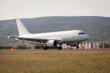 Fototapeta na wymiar White passenger plane is landing on the airport.