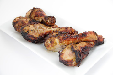 Grilled chicken legs (drumsticks) on white plate