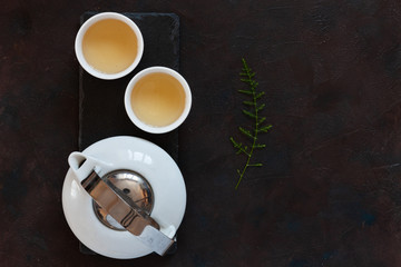 White porcelain Asian tea set with green tea Milk Oolong on black stone desk. Close up, top view.