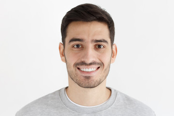 Fototapeta premium Close-up portrait of smiling handsome unshaven man isolated on gray background