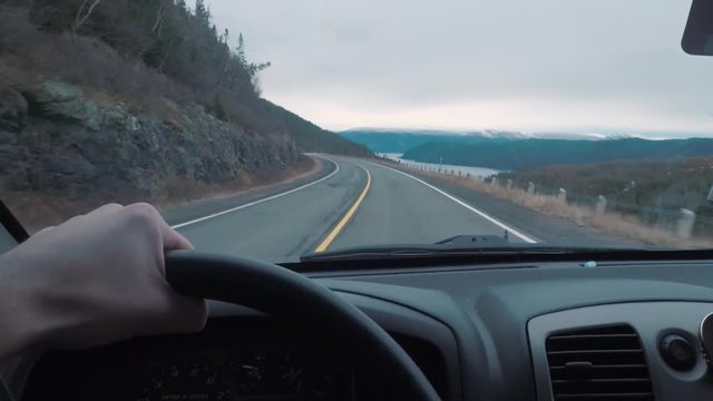 Driving POV on top of a mountains peak. The window view is larger mountains in the distance.