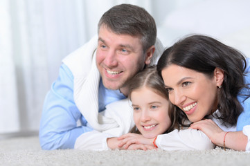 Fototapeta premium Happy parents and daughter lying on floor in room