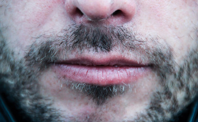 Beautiful thin men's lips and light unshaven face close up
