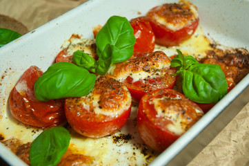Closeup detail look on fresh vegetarian sliced and salted tomatoes ready to bake covered with cheese and fresh organic basil