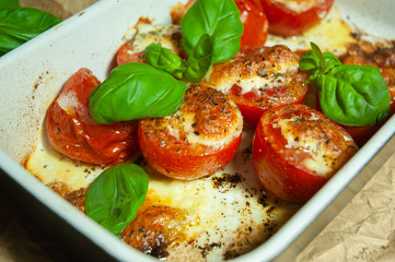 Closeup detail look on fresh vegetarian sliced and salted tomatoes ready to bake covered with cheese and fresh organic basil