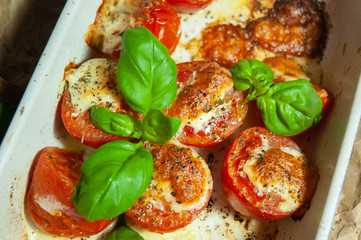 Closeup detail look on fresh vegetarian sliced and salted tomatoes ready to bake covered with cheese and fresh organic basil