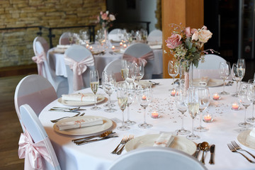 Wedding. Banquet. The chairs and round table for guests, served with cutlery, flowers and crockery and covered with a tablecloth.