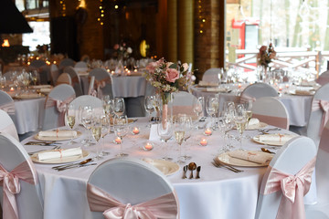 Wedding. Banquet. The chairs and round table for guests, served with cutlery, flowers and crockery and covered with a tablecloth.