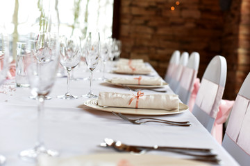 Wedding. Banquet. The chairs and round table for guests, served with cutlery, flowers and crockery and covered with a tablecloth.
