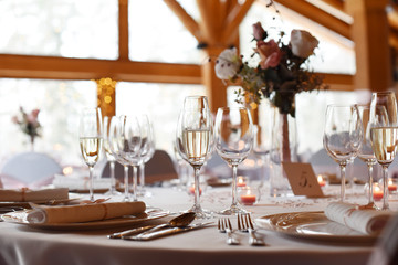 Wedding. Banquet. The chairs and round table for guests, served with cutlery, flowers and crockery and covered with a tablecloth.