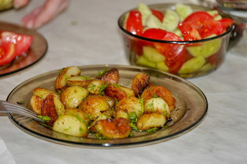 fried chicken with dill roast on a glass plate, In the background with a salad with cucumbers and tomatoes.
