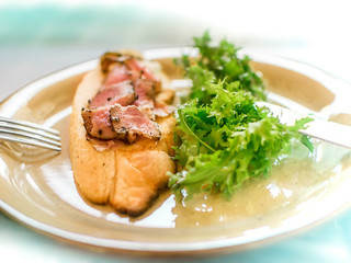 Round plate with appetizing open sandwich with toast and pieces of smoked fish and fresh green leaves of arugula