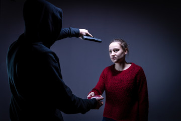 Ein Mann mit Pistole nimmt Geld von einer Frau